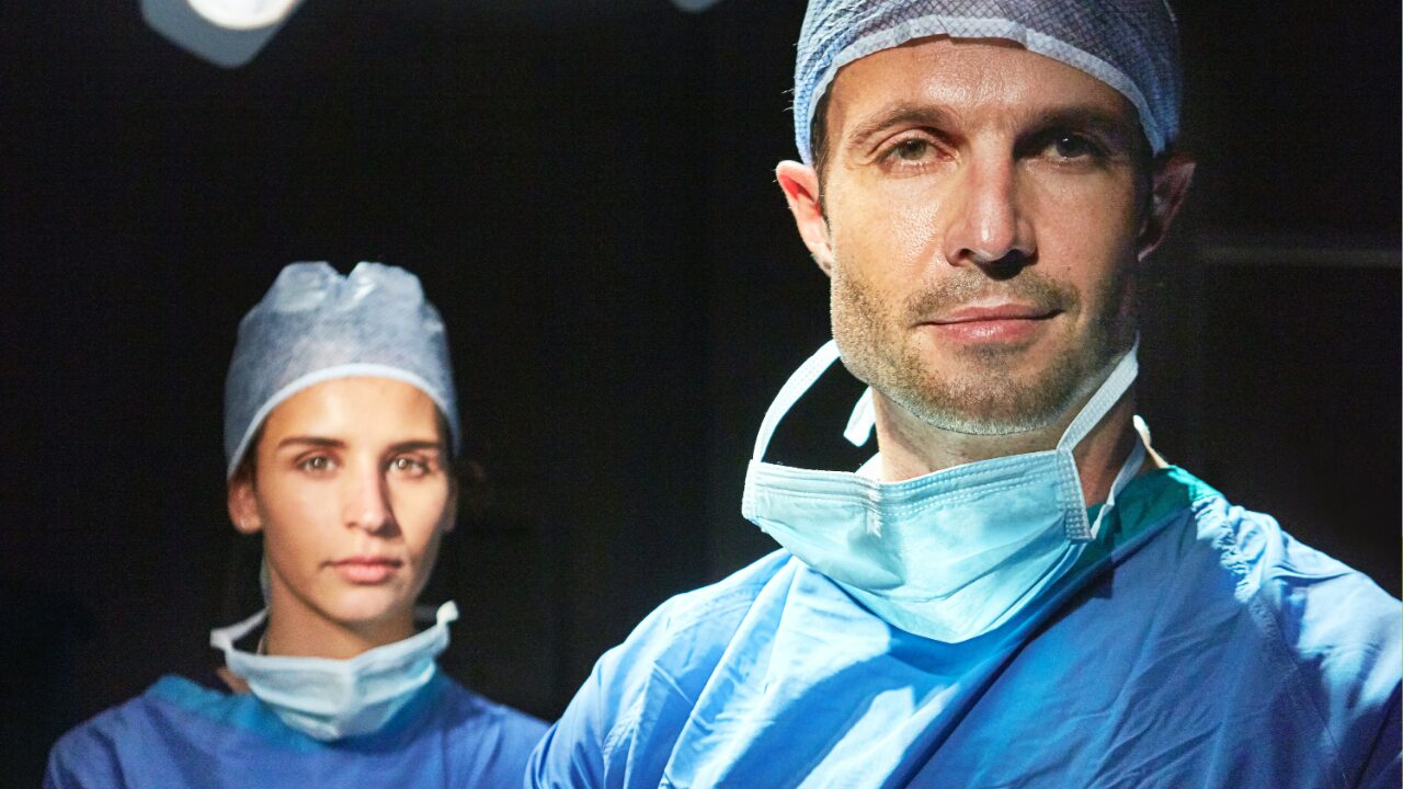 Two consultant surgeons in theatre scrubs and caps